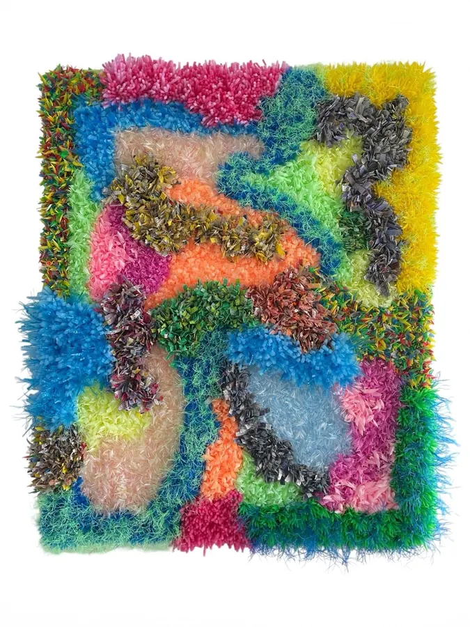 Textile piece of tufted yarn in bright pink, blue, green, and yellow
