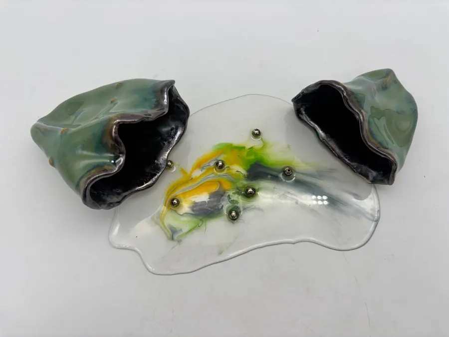 Sculpture of two green ceramic vessels joined by a clear pool of resin