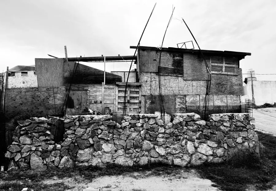 Black and white photograph of a makeshift shack built on a stone wall