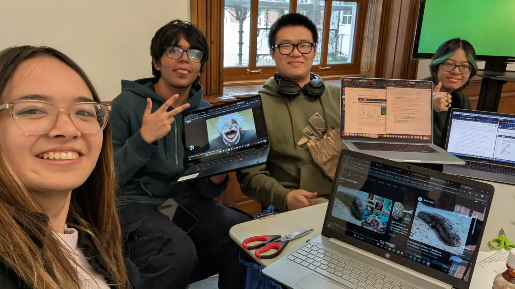 Members smiling around a table of laptops showing digital artwork