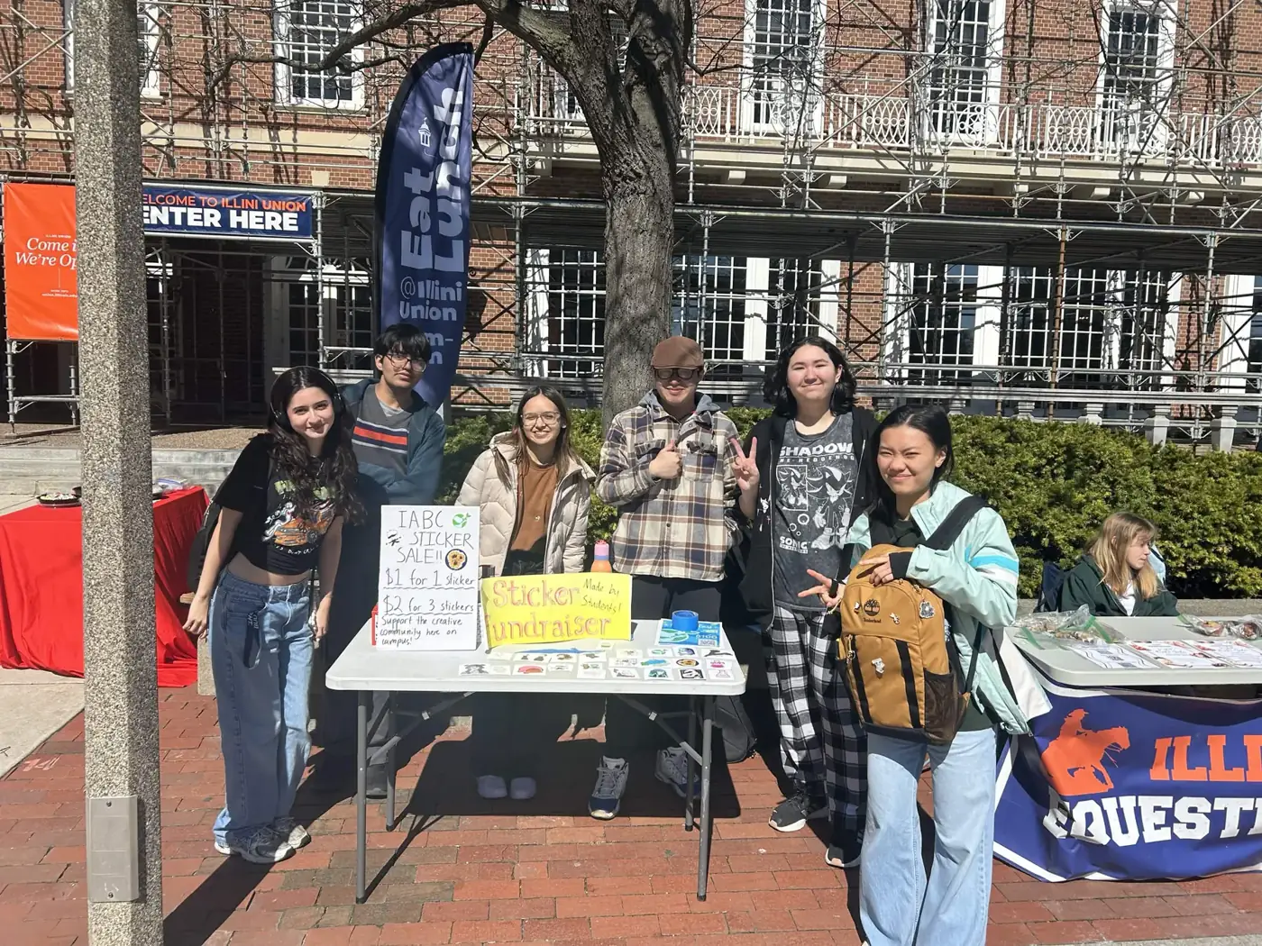 Members standing behind a sticker sale fundraiser table outside the Illini Union