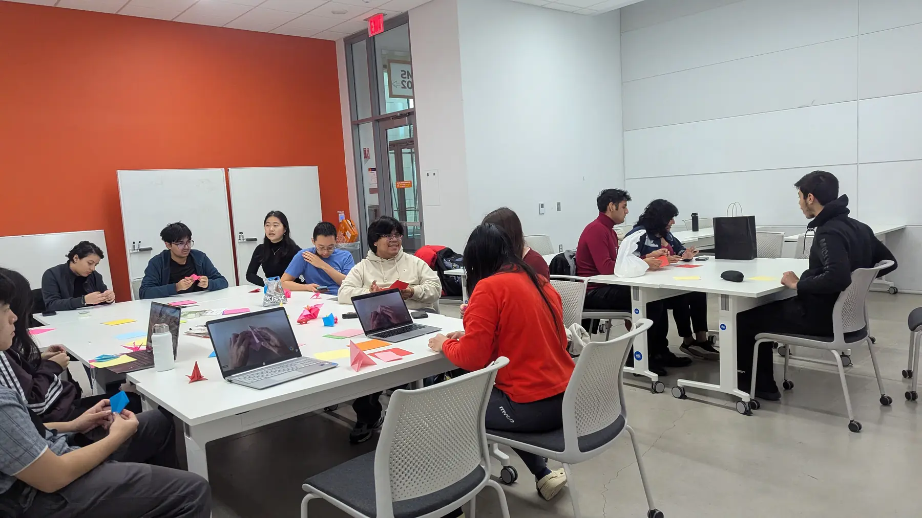 Students making paper crafts together at tables during a club social